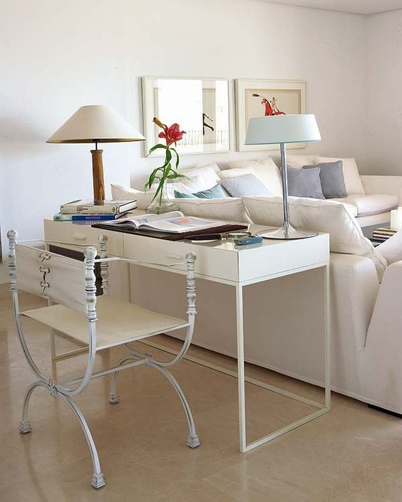 a sleek white desk and an airy chair behind the sofa match the space and even make it more refined and chic