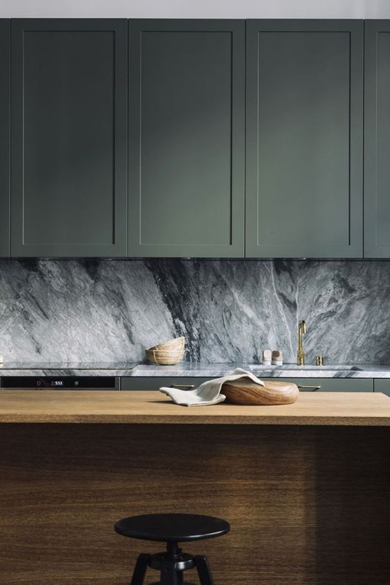 sage cabinets, a grey marble backsplash and a wooden kitchen island compose a chic and refined modern look
