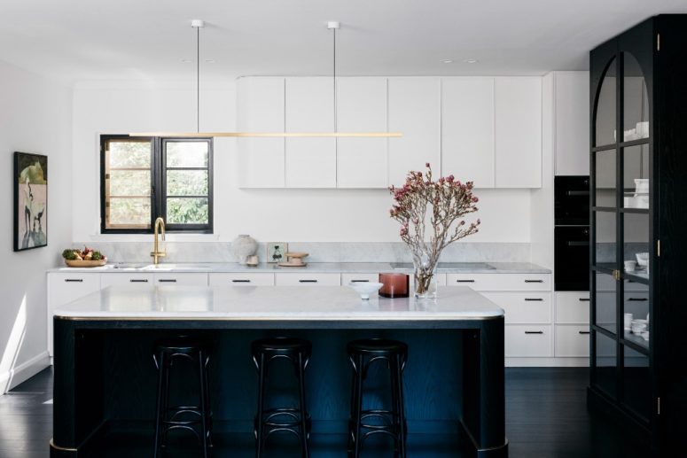 the kitchen features amazing white cabinets and surfaces spruced up with gilded touches and given depth with black details