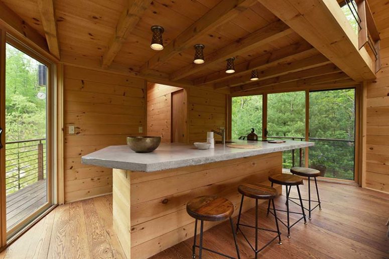 kitchen with a super large kitchen island The kitchen is done with a large kitchen island topped with a concrete countertop and some pendant lamps