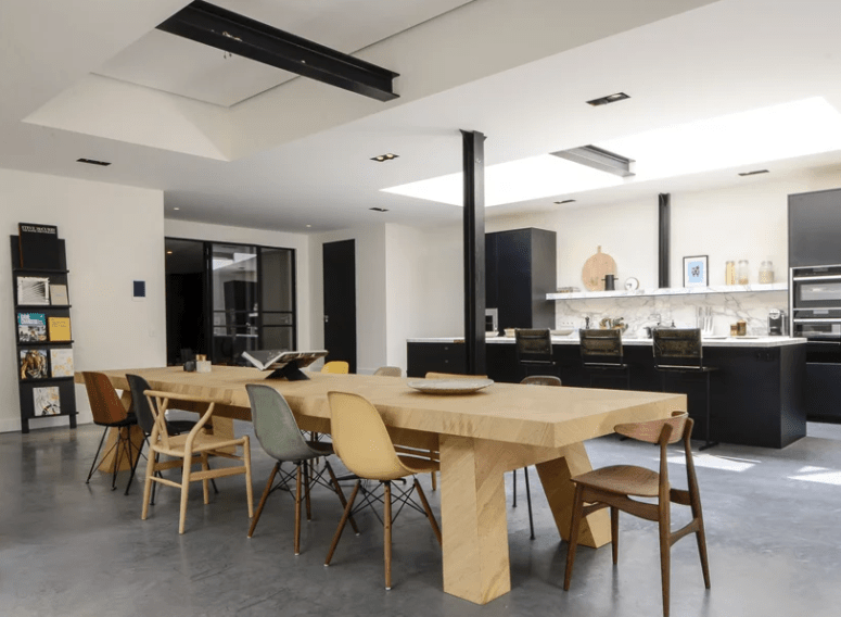 The kitchen is done with black cabinets and white countertops and the dining zone features a sculptural wooden table