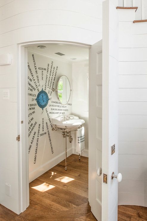 a creative sea-inspired powder room with a window, an artwork on the wall and a round mirror