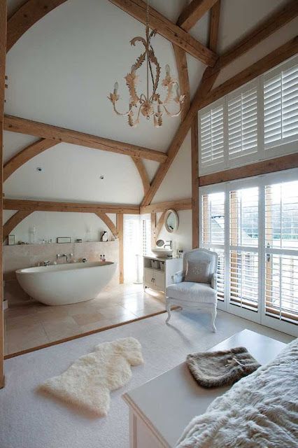a gorgeous refined space with wooden beams and a bathtub zone done with large scale tiles