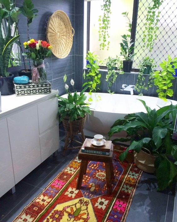 the bedroom is given a strong boho feel with potted greenery, a colorful rug and a wall basket