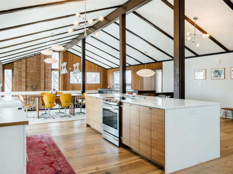 The upper part contains ad kitchen with white and light colored wood furniture and a dining zone with a wooden table and yellow chairs The upper part contains ad kitchen with white and light-colored wood furniture and a dining zone with a wooden table and yellow chairs