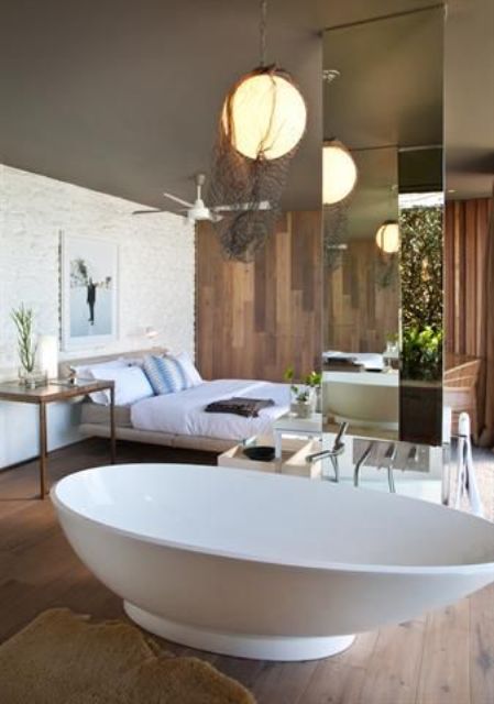 a gorgeous coastal bedroom with a shell-shaped free-standing bathtub  separated with a mirror pillar