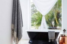 05 a serene boho chic bathroom with a boho rug, a free-standing bathtub, a Moroccan lantern and a copper side table