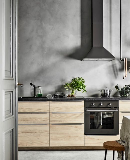 lower cabinets of light-colored wood and a concrete wall look interesting and contrasting