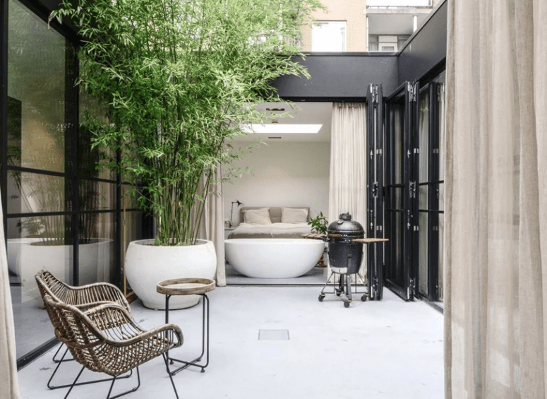 cool outdoor rattan furniture The patio features a grill, an oversized plant in a pot and a sitting zone with rattan furniture