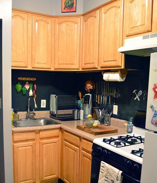 a light-colored kitchen with stone countertops and a chalkboard backsplash that add texture to the space