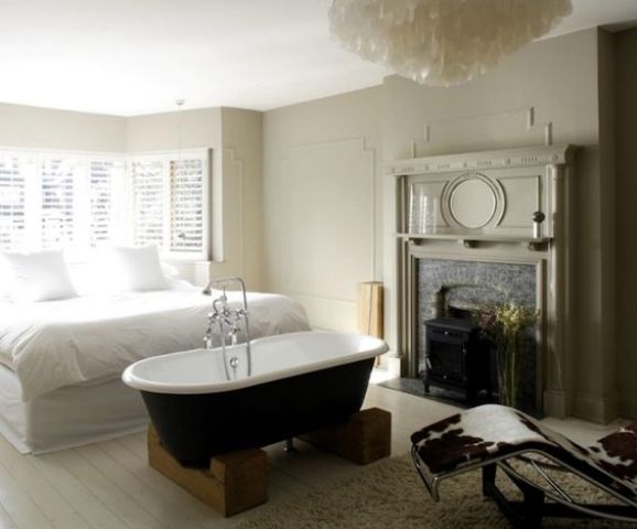 a modern meets vintage bedroom with a vintage tub on wooden stands and a vitnage fireplace restored