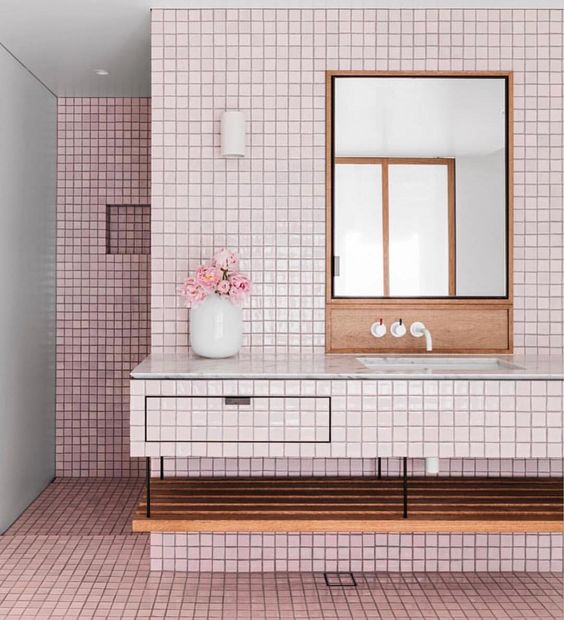 glossy light pink tiles covering the floor and walls are calmed down with warm-colored wood and white touches
