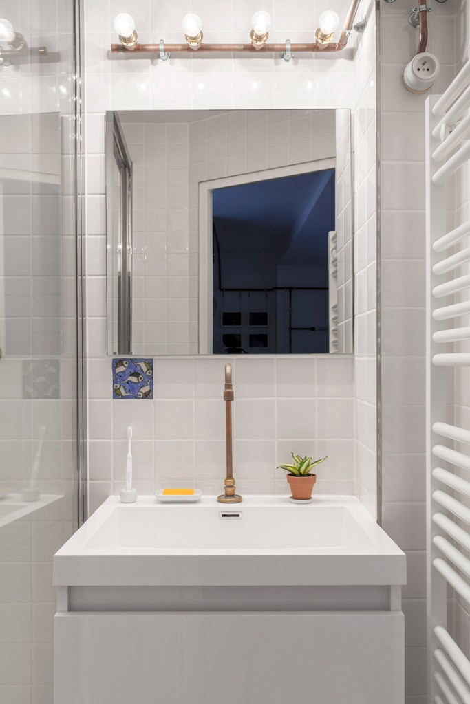The bathroom is also done in white, with white tiles and a radiator, and here the copper pipes show off some bulbs