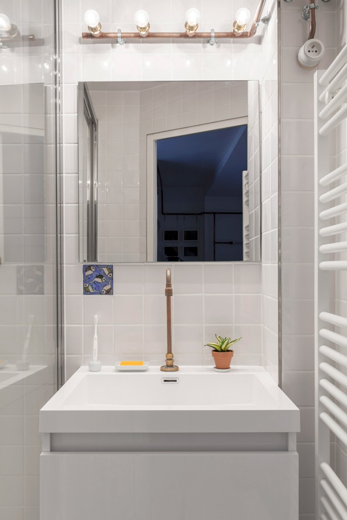 stylish radiator in a bathroom The bathroom is also done in white, with white tiles and a radiator, and here the copper pipes show off some bulbs