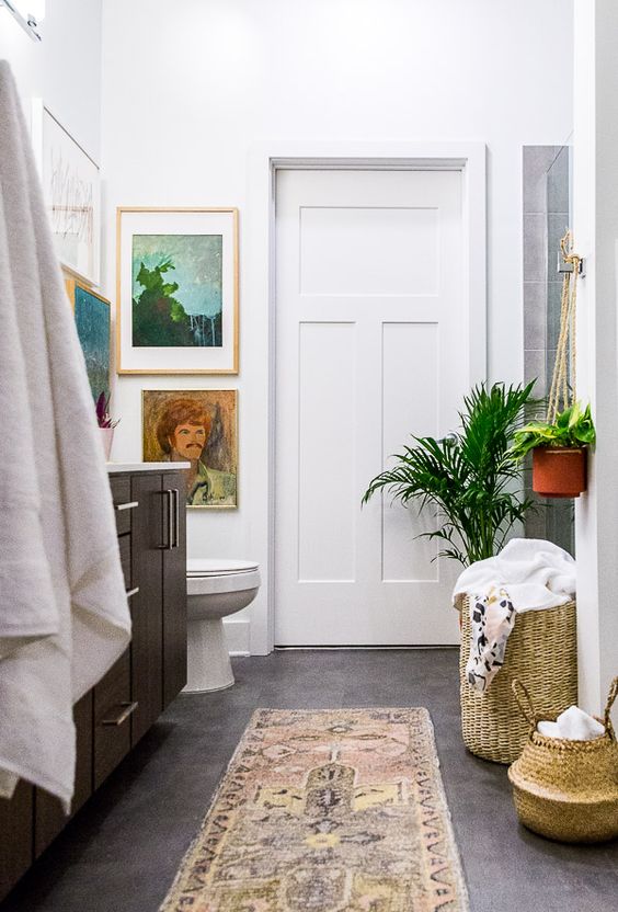 a boho rug, baskets with towels, potted plants and some artworks make this bathroom boho chic