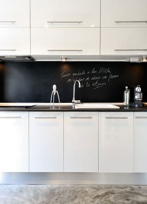 una moderna cucina bianca con un nero lavagna backsplash che aiuta a stare fuori e aggiunge profondità