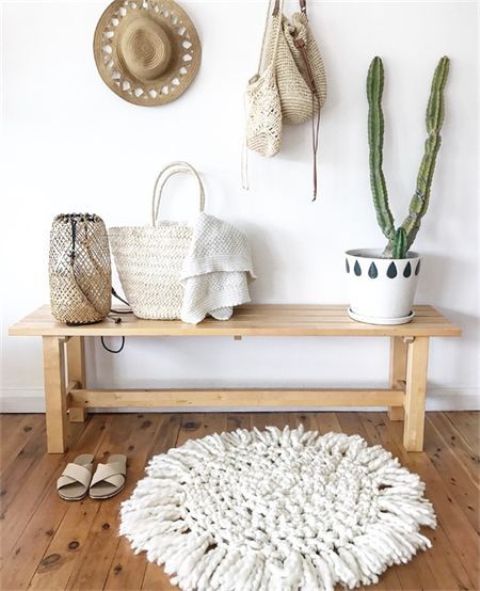 a wooden bench, a woven rug, cacti in pots, a candle lantern and some hats