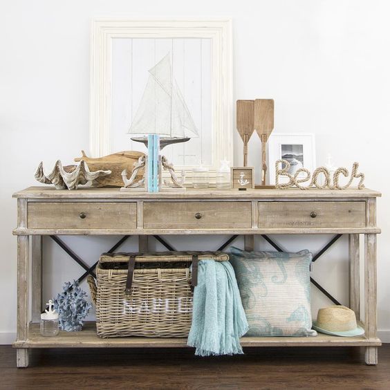 a wooden console with oars, shells, driftwood, rope, artworks and a basket for storage