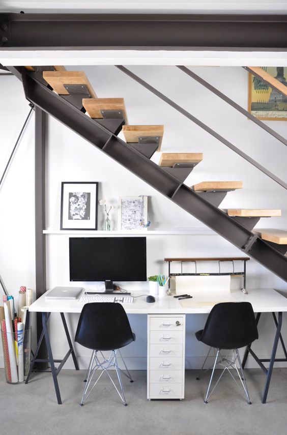 an industrial shared workspace with a metal and wood staircase that doesn't prevent light from coming inside