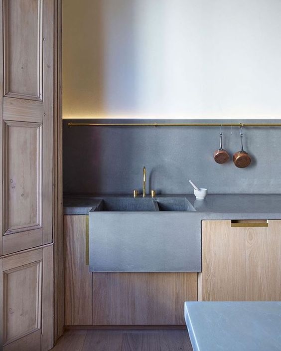 a peaceful minimalist kitchen with light-colored cabinets and concrete countertops and a backsplash