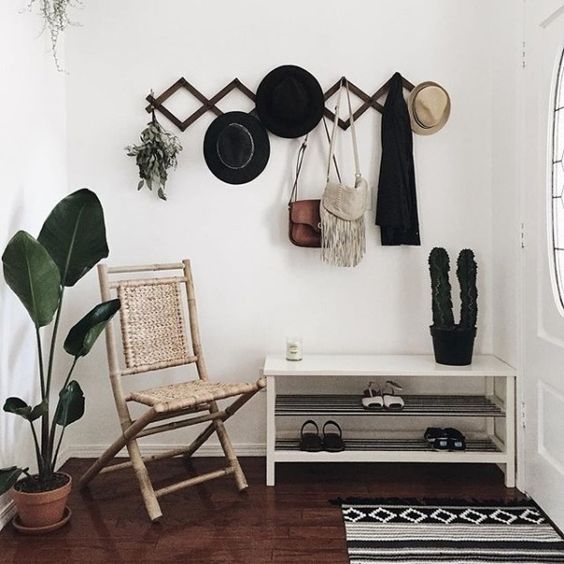 a simple shoe shelf, a woven chair, a geometric hanger on the wall and a geo rug