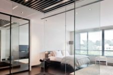 13 a contemporary bedroom with a large dark metal sunken bathtub separated with glass to avoid splashes on the floor