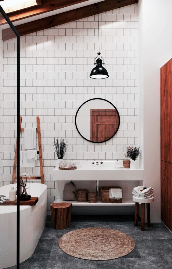 a boho space with white tiles, a jute rug, wooden items and baskets and a white concrete vanity