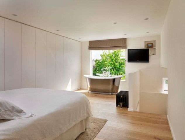 a contemporary bedroom with sleek storage cabinets and a metal free-standing bathtub by the window
