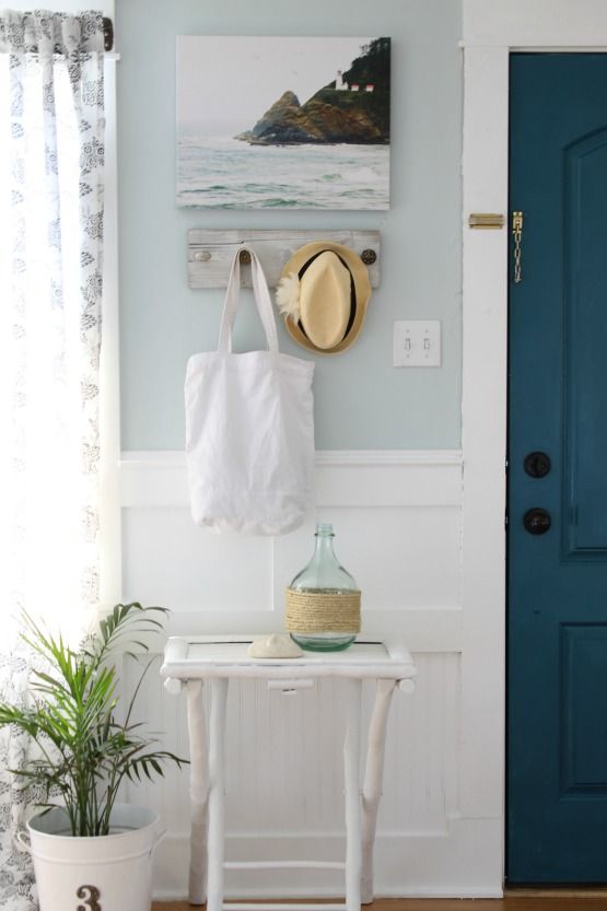 a tiny console table with a yarn wrapped bottle, an artwork and a little shelf