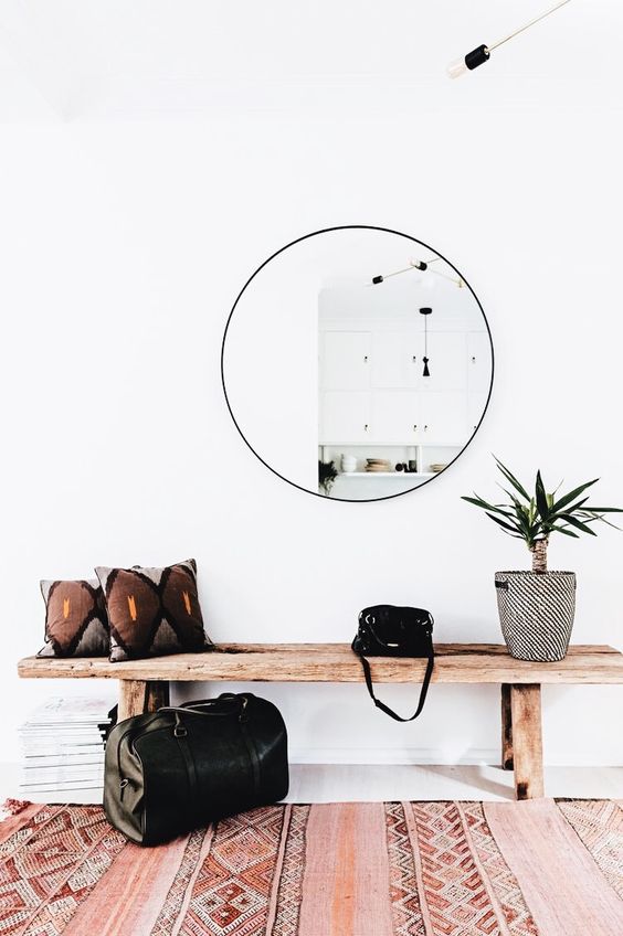 a boho rug, a round mirror, a wooden bench and a potted plant are all you need for a simple look
