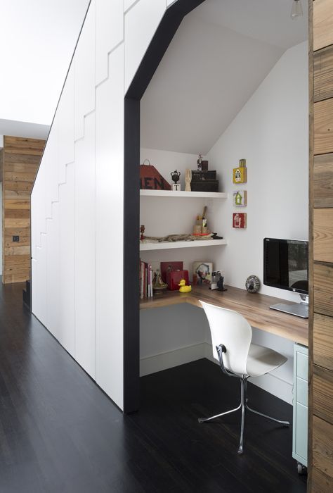 a contemporary home office space built inside a staircase with a built-in desk, shelves and a chair