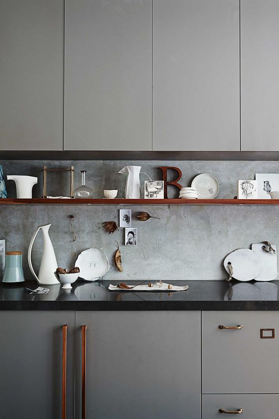 a grey kitchen with a black countertop and a concrete backsplash for a textural look