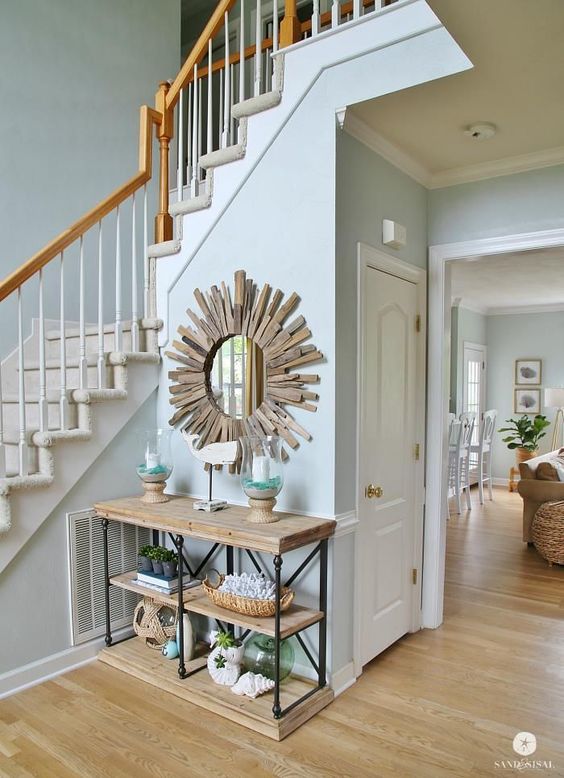 a simple vintage console, baskets, lanterns, corals, a whale art and a wood clad sunburst mirror