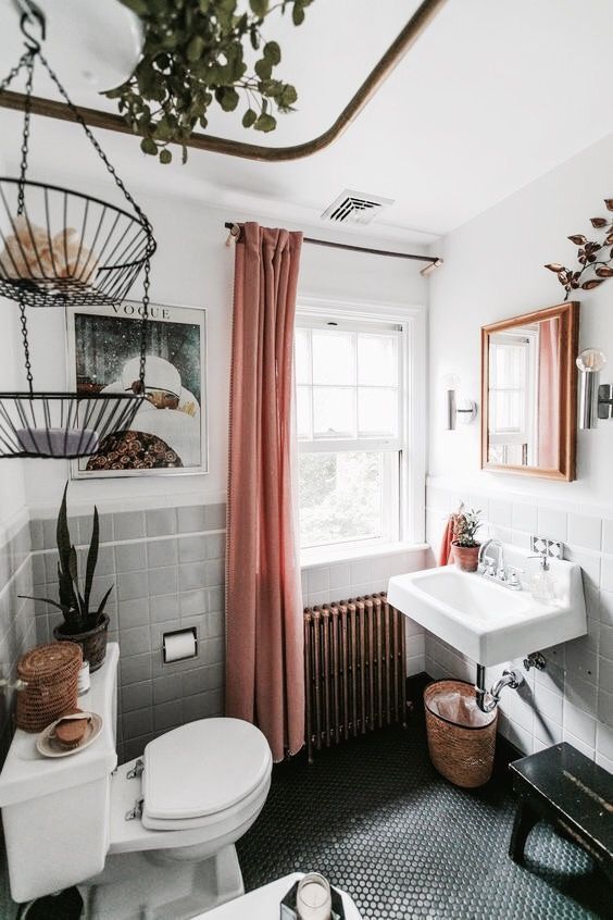 baskets, penny tiles on the floor, potted plants and greenery and a metal hanging shelf make the space boho