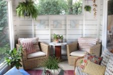 16 a boho screened porch with lights, hanging potted greenery, rattan and wooden furniture, a colorful rug