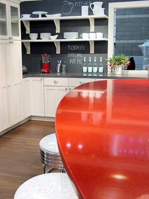 una cocina blanca, una pizarra, un protector contra salpicaduras y una red mesa de comedor para un look atrevido