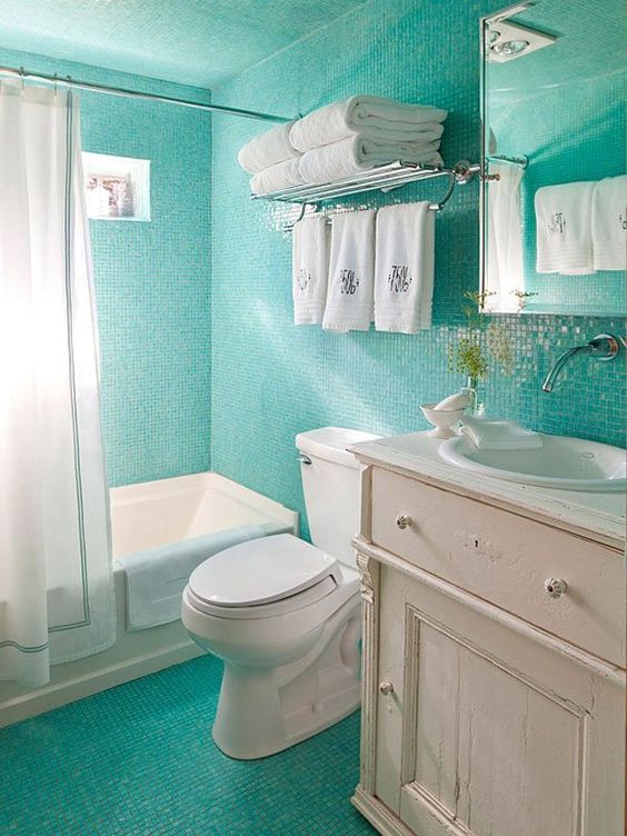 small turquoise bathroom tiles that cover the walls and the floor and contrast whites used in decor