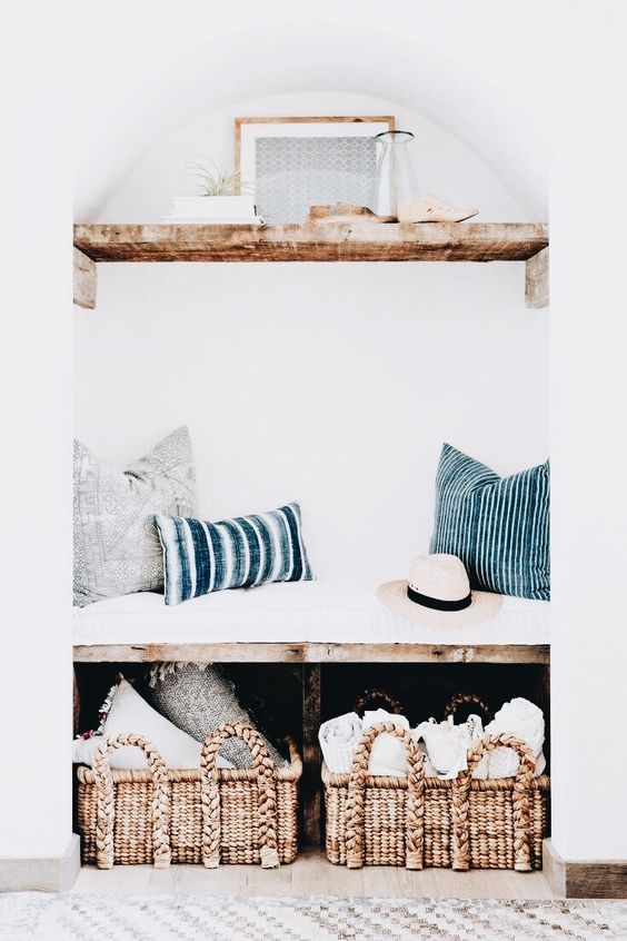 a built-in bench with baskets for storage and a shelf with airplants over the bench for a small entryway
