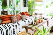 18 a colorful boho porch with a wicker lampshade, printed and colorful textiles, potted greenery and lanterns