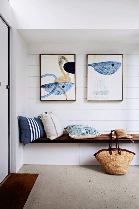 a built-in bench with storage, watercolor artworks over the bench, printed pillows for a simple look