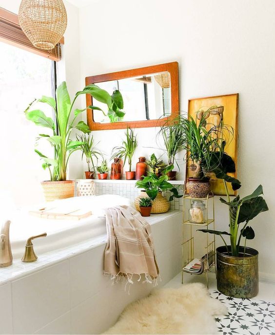 a boho space with potted greenery and plants, an artwork, a mirror and a wicker lampshade