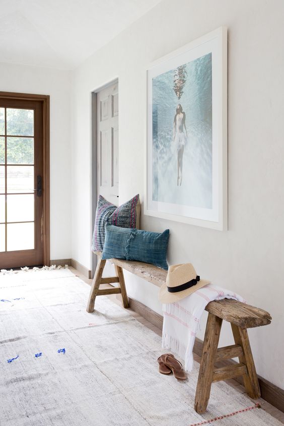 a reclaimed wood bench with trestle legs, chambray pillows, a sea-inspired artwork over the bench