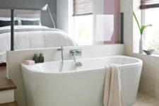 22 a small and comfy bedroom features a bathtub, which is separated with a concrete and glass space divider