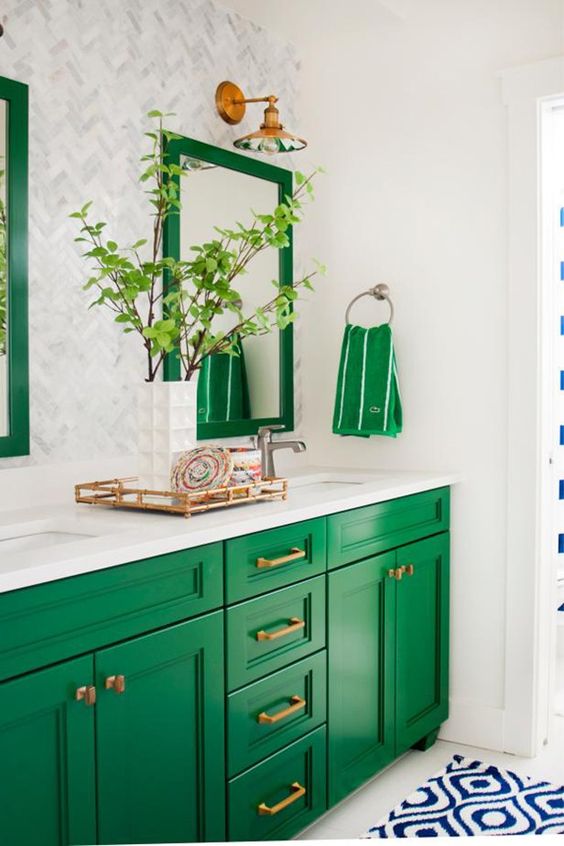 an emerald sink stand and framed mirrors add color to the space and are spruced up with brass touches