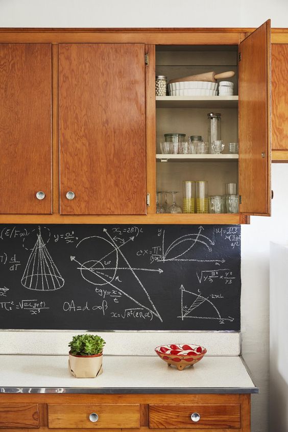rich-colored wooden cabinets and a chalkboard backsplash with formulas that personalize the decor
