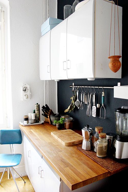 un accogliente piccola cucina bianca con un colore chiaro piano di lavoro e una lavagna backsplash che aggiunge un tocco di stile