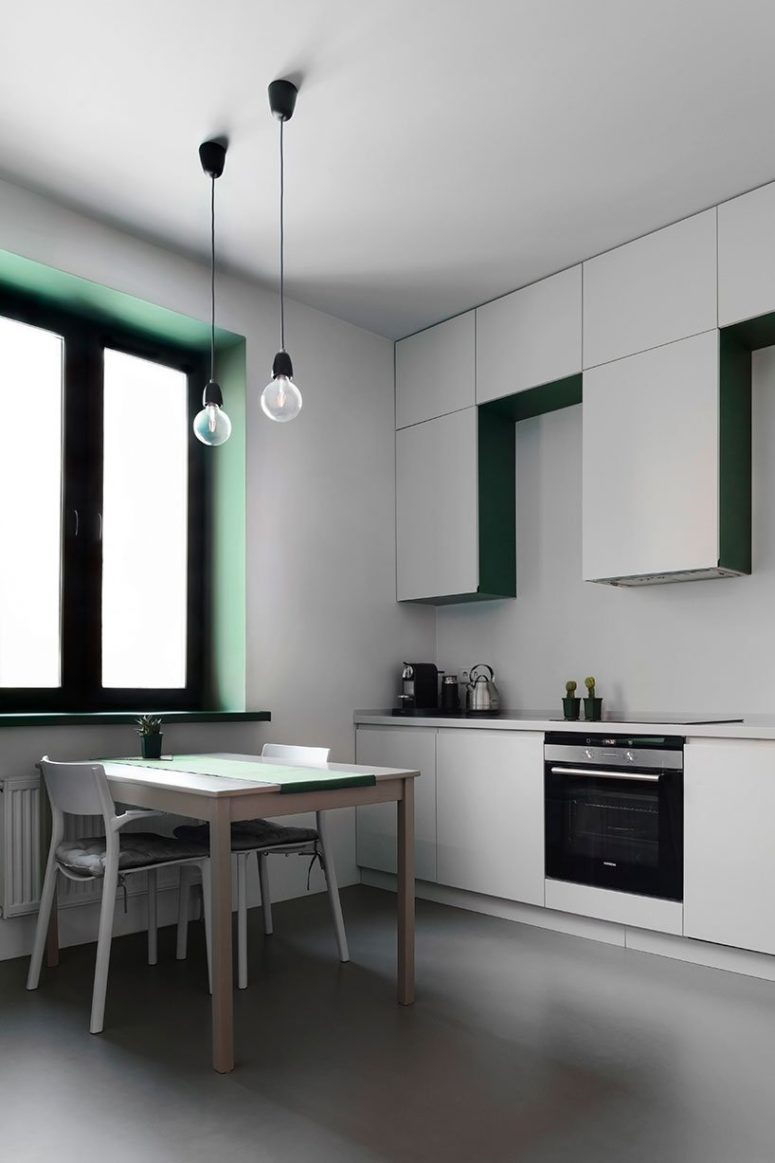 The kitchen is done with sleek white cabinets, a simple table and chairs and toiches of emerald here and there, plus there are two pendant lamps over the table The kitchen is done with sleek white cabinets, a simple table and chairs and toiches of emerald here and there, plus there are two pendant lamps over the table