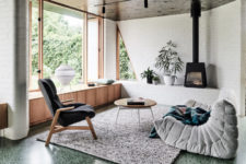 The living space is done with white brick walls, dark stained ceilings, there’s a wooden windowsill bench plus a hearth and comfy chairs