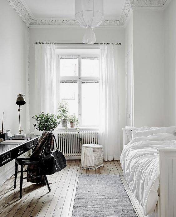 a serene and airy guest bedroom with lots of white and a vintage black desk plus chair to stand out