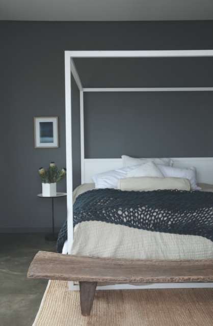 minimalist guest room design A guest bedroom is done with a graphite grey statement wall, a wooden bench and a framed bed plus textiles